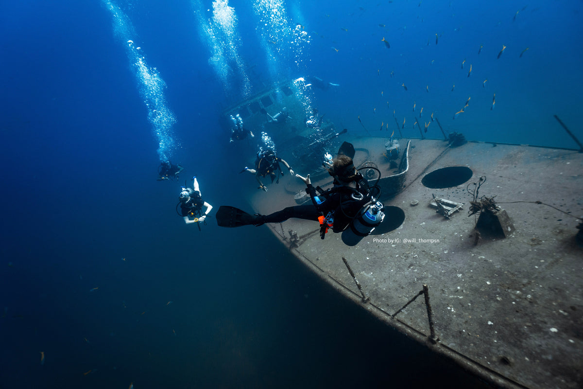 a woman freediving in the ocean, seen from behind, wearing a billybun hair wrap